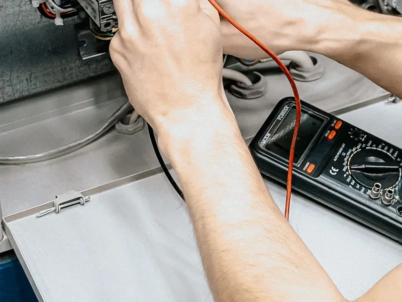 Electrician testing a circuit with a multimeter during an electrical repair in Owasso, OK